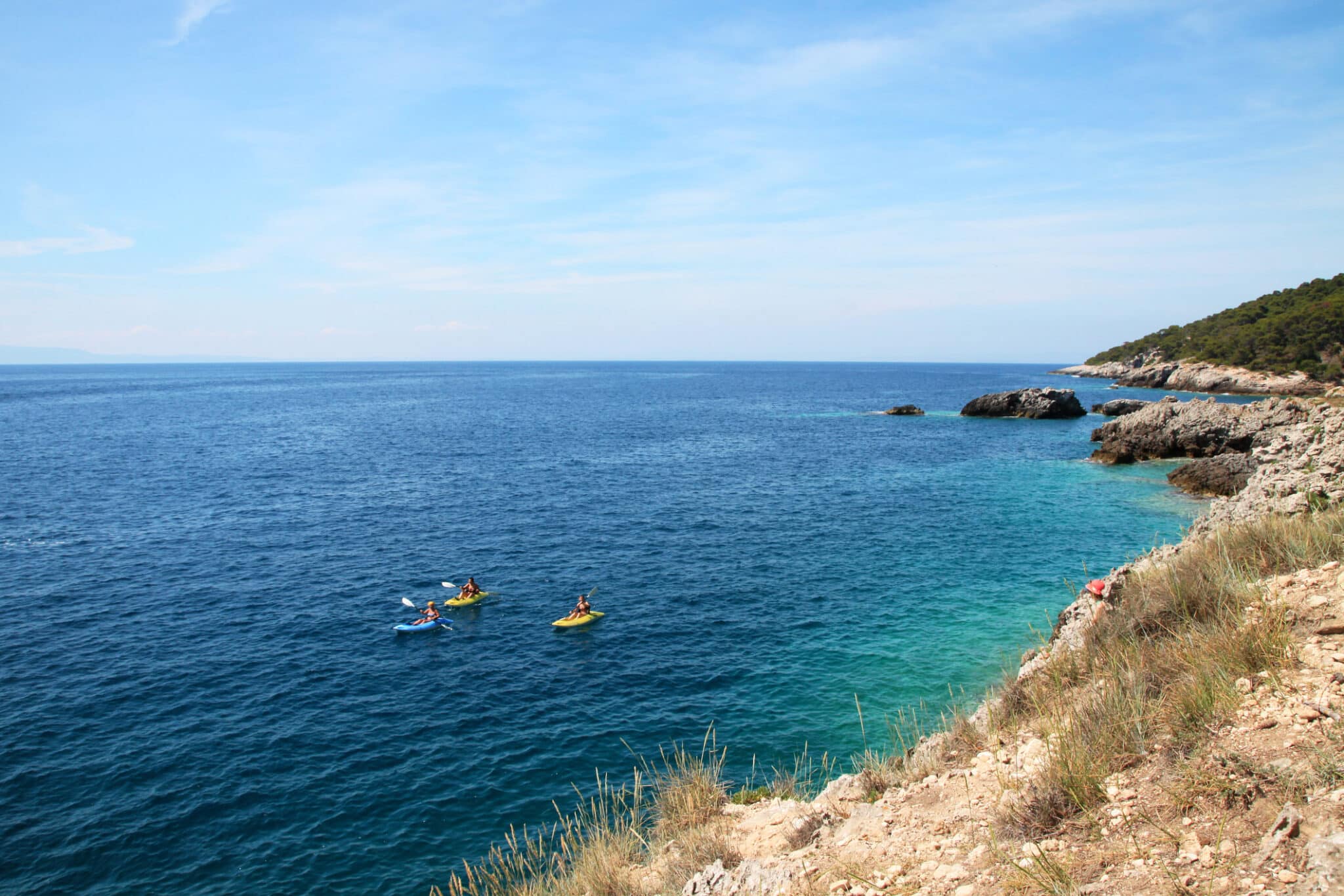 Canoisti esplorano mare azzurro e costa rocciosa