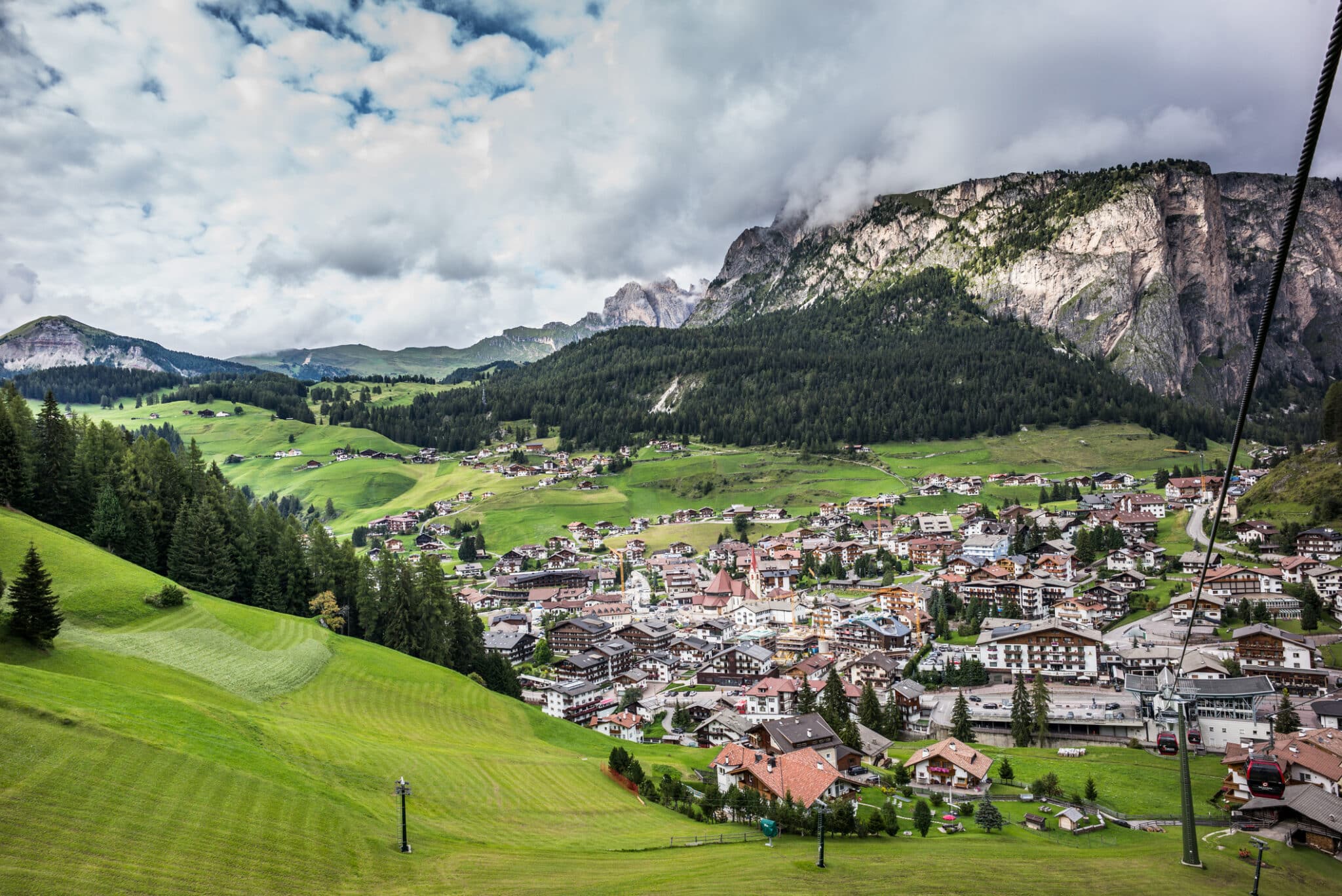 Panoramica paesino montano, prati verdi e montagne nuvolose