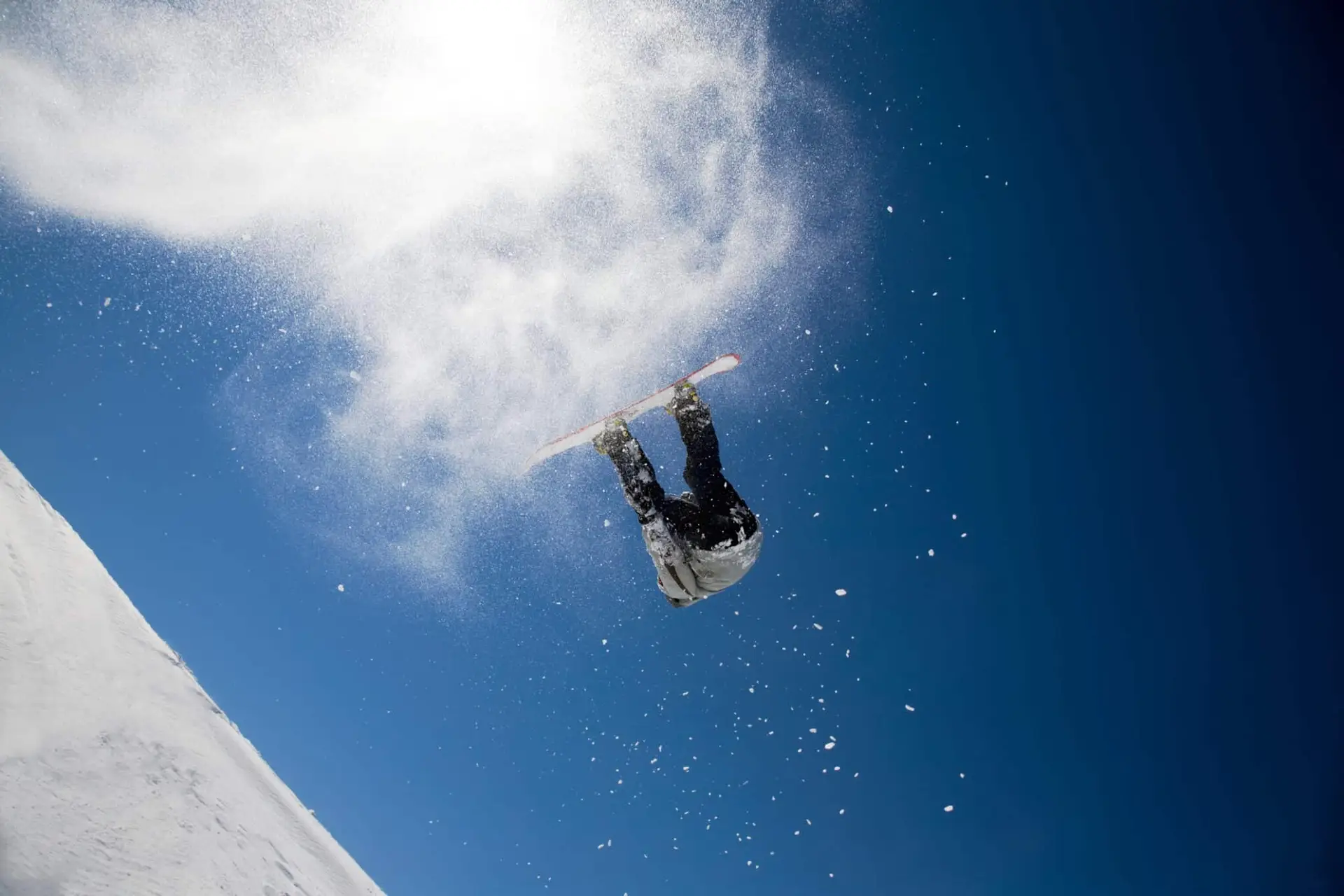 Snowboarder esegue acrobazia sotto cielo azzurro