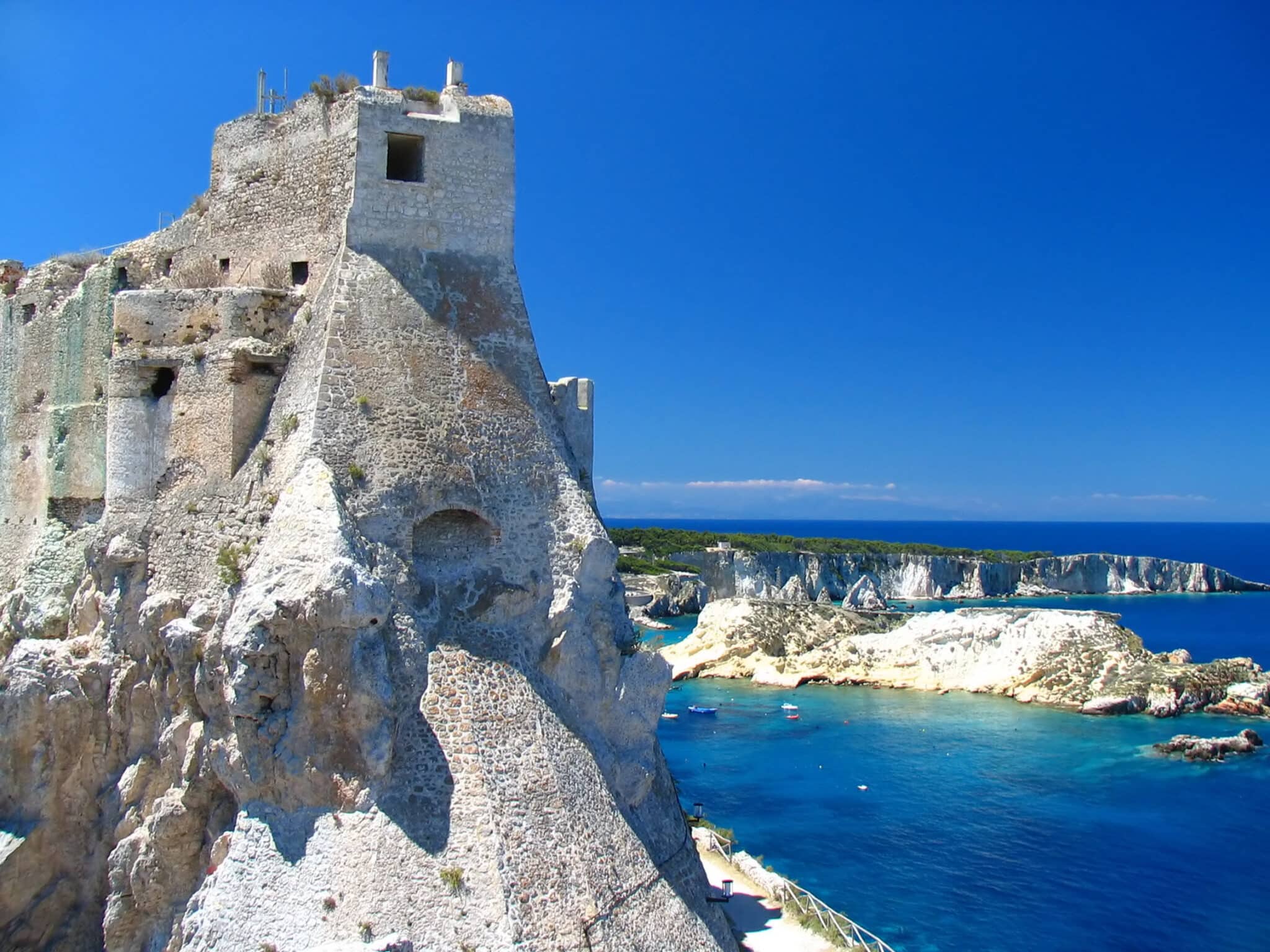 Castello antico su scogliere costiere, mare blu limpido