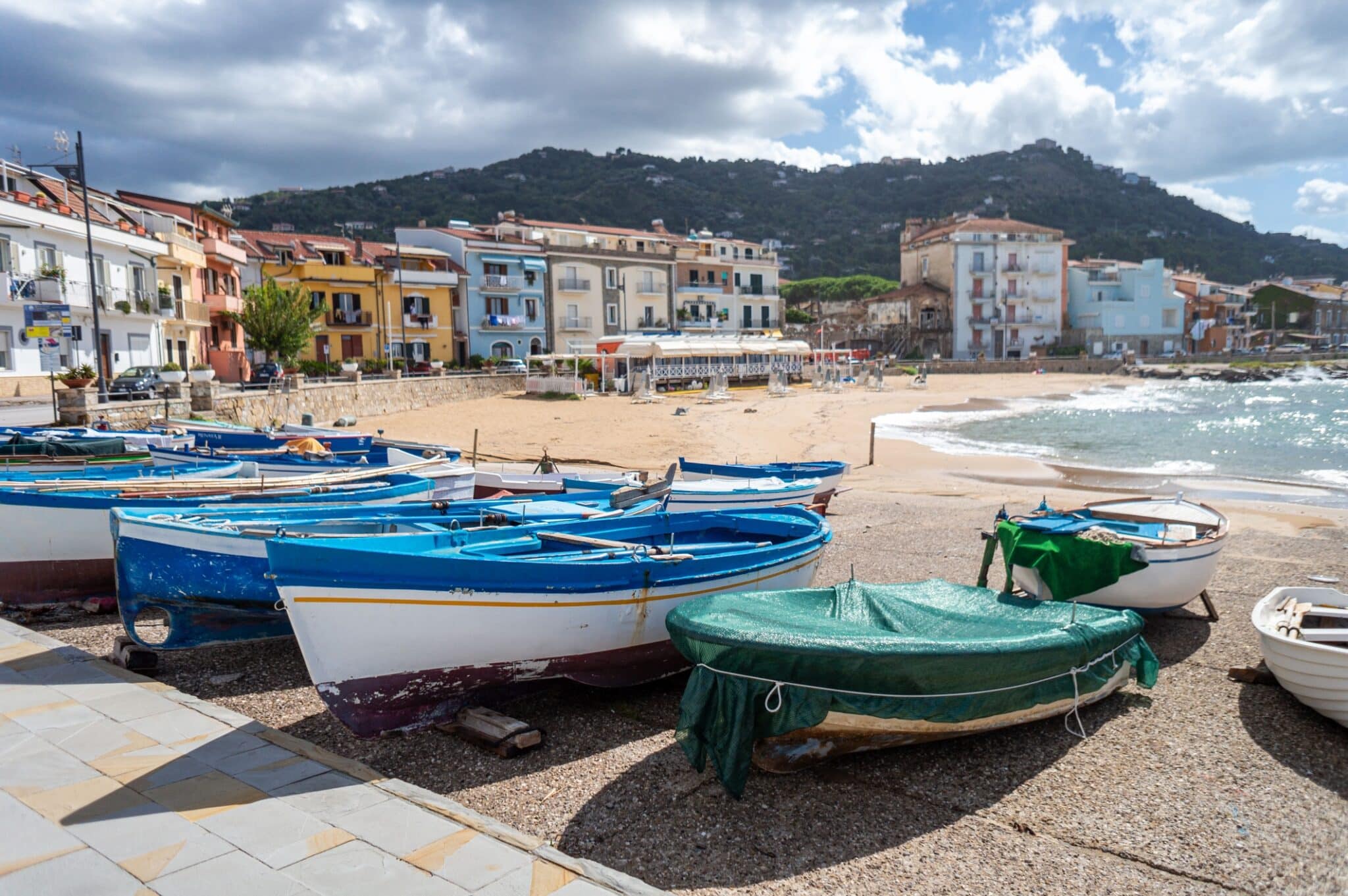 Barche colorate sulla spiaggia, paese costiero sullo sfondo