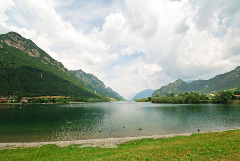 Lac clair entouré de montagnes vertes et d'un ciel nuageux