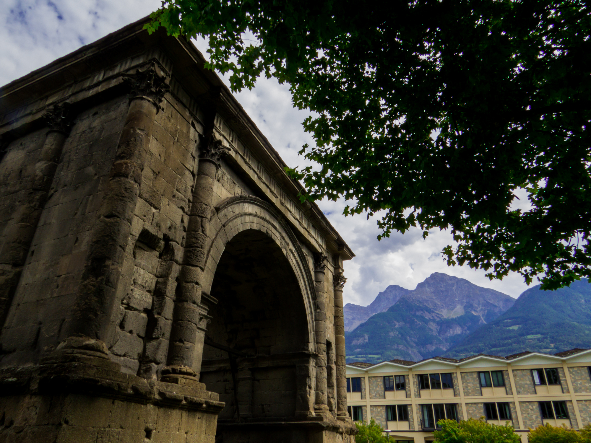 Arco antico con montagne sullo sfondo e foglie verdi