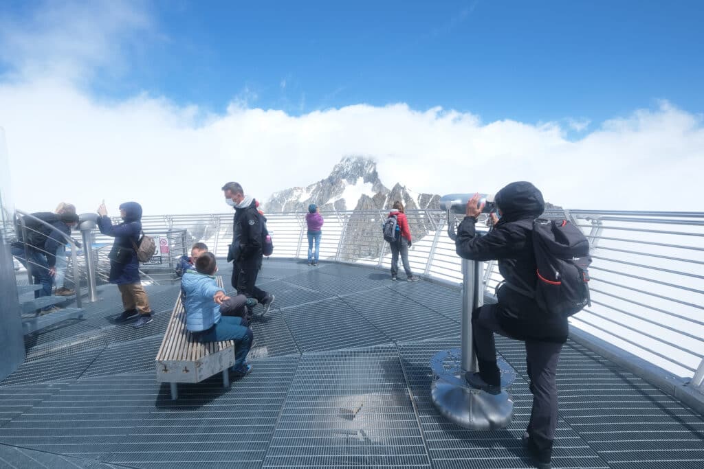 Des touristes observent les montagnes enneigées depuis une plate-forme d'observation