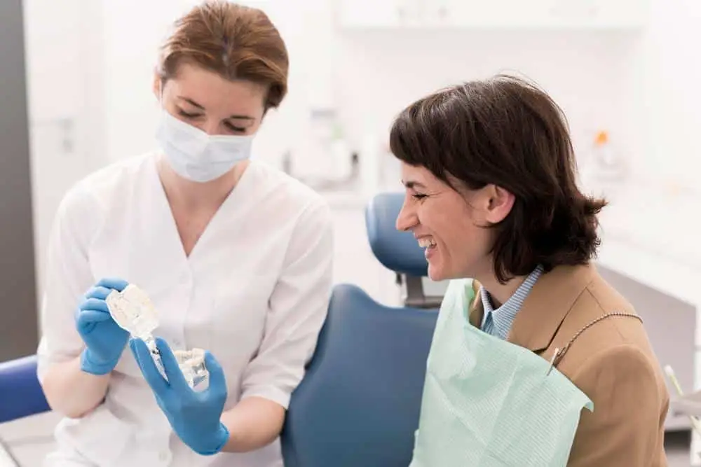 Dentista mostra modello dentale a paziente sorridente